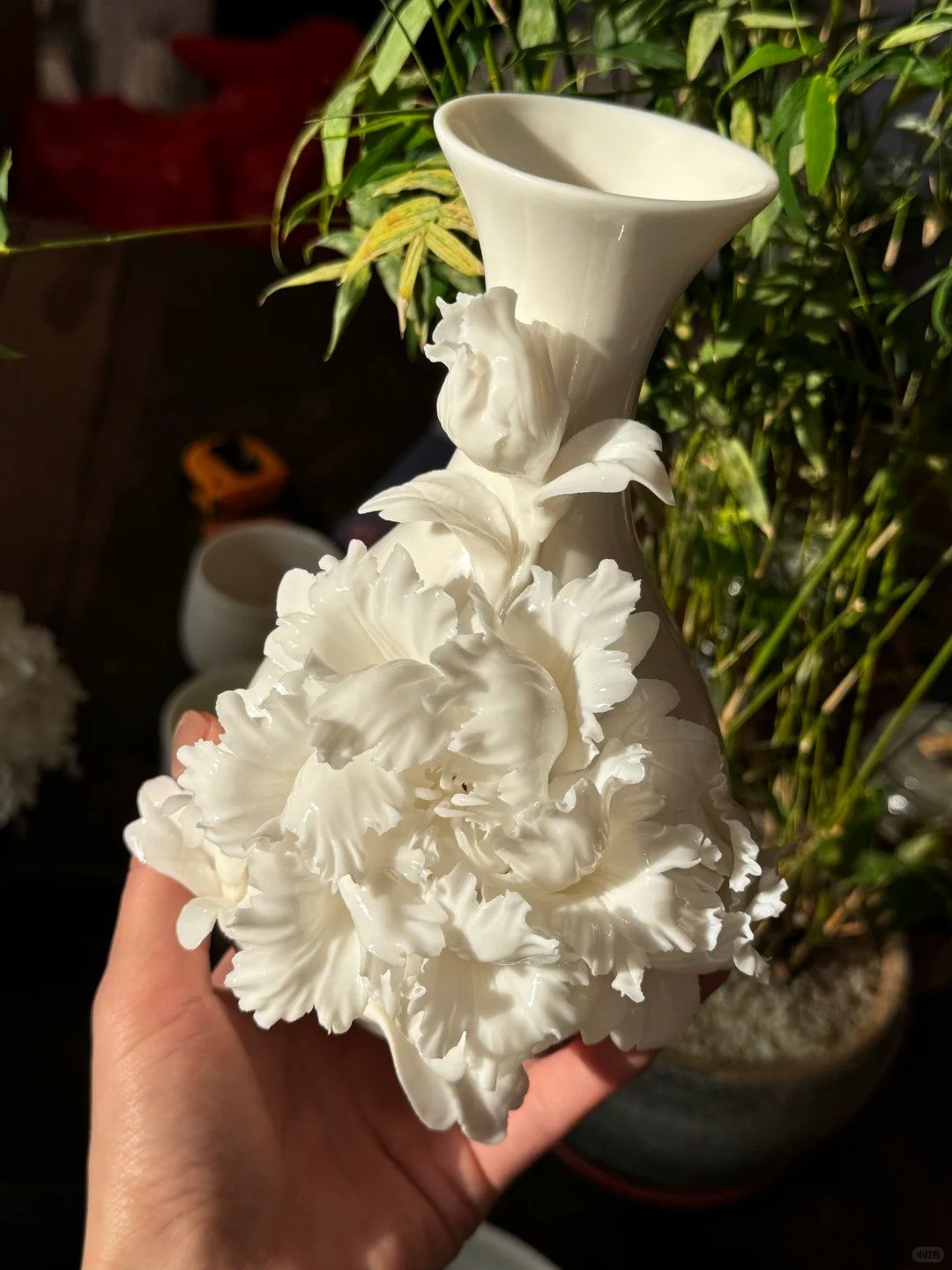 White porcelain vase decorated with full white peony ceramic flowers and green leaves
