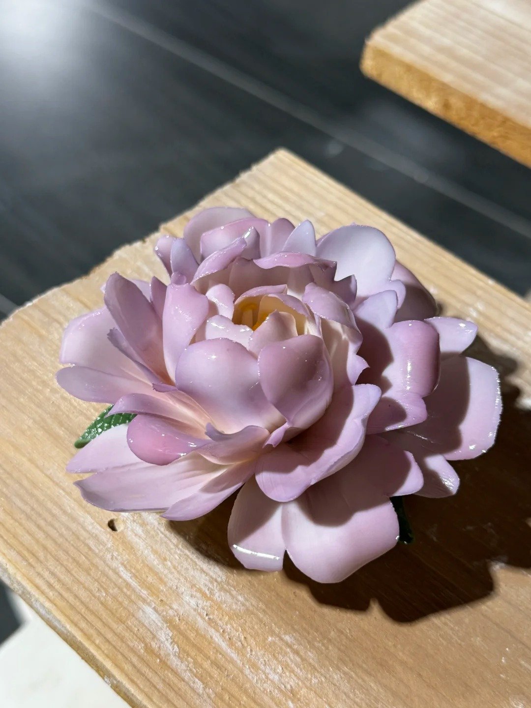 Hand holding a purple peony ceramic flower with layered petals