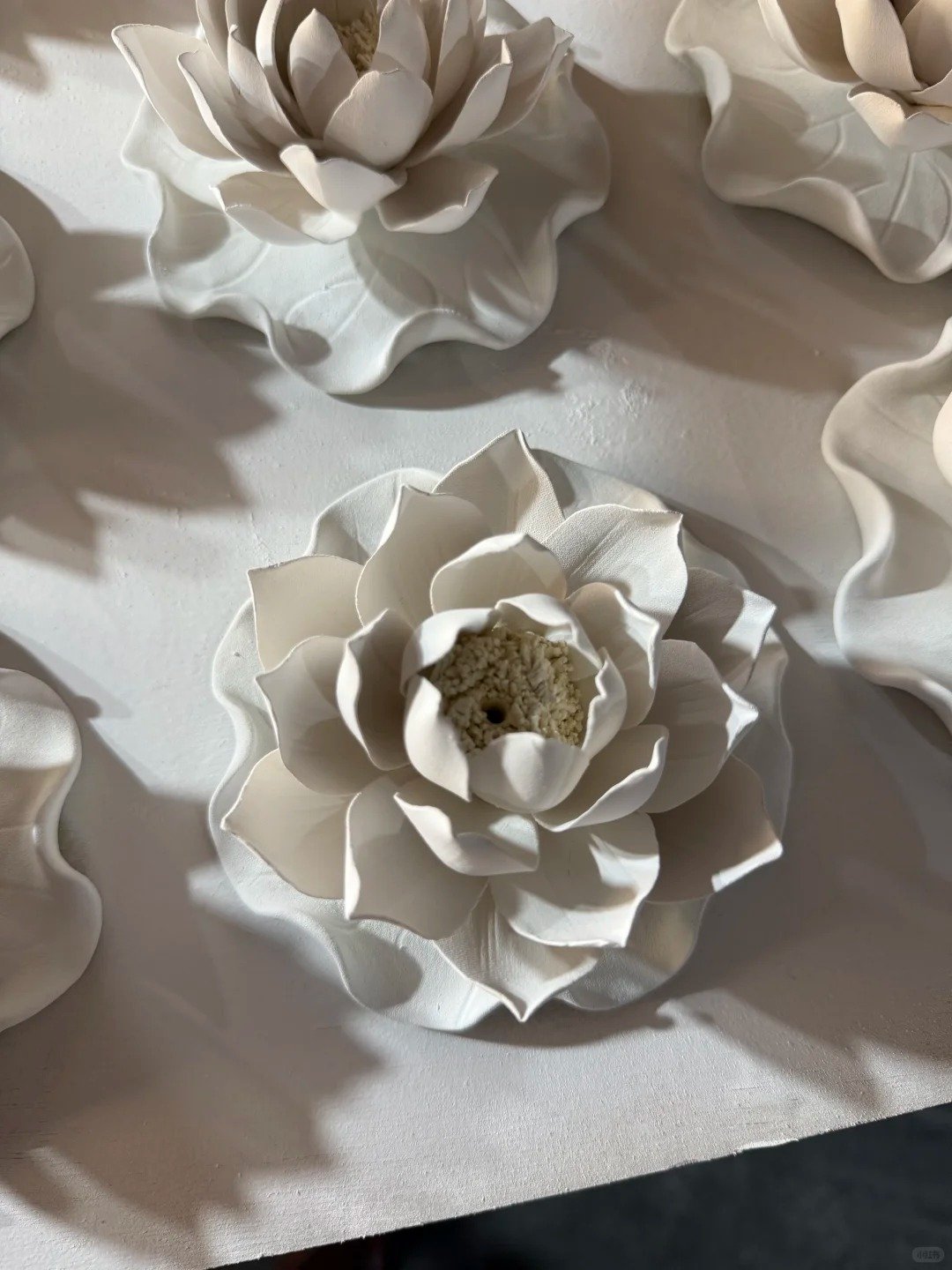 White porcelain lotus ceramic incense holder photographed on a dark surface