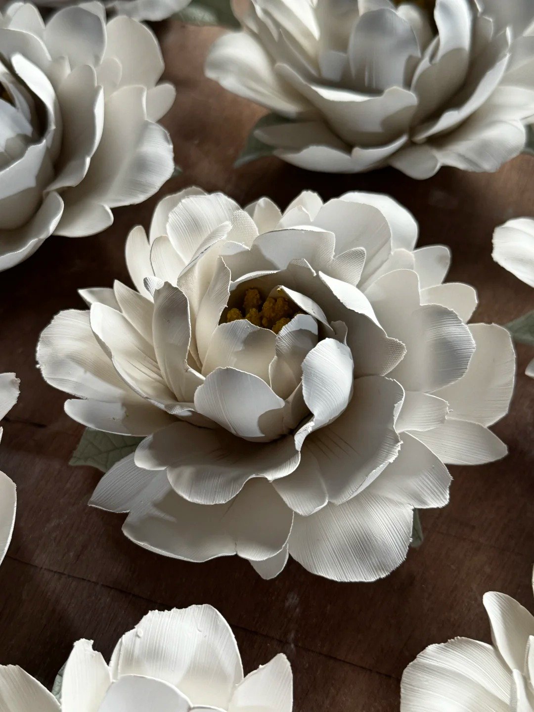 White peony ceramic incense holder with layered petals on a wood surface
